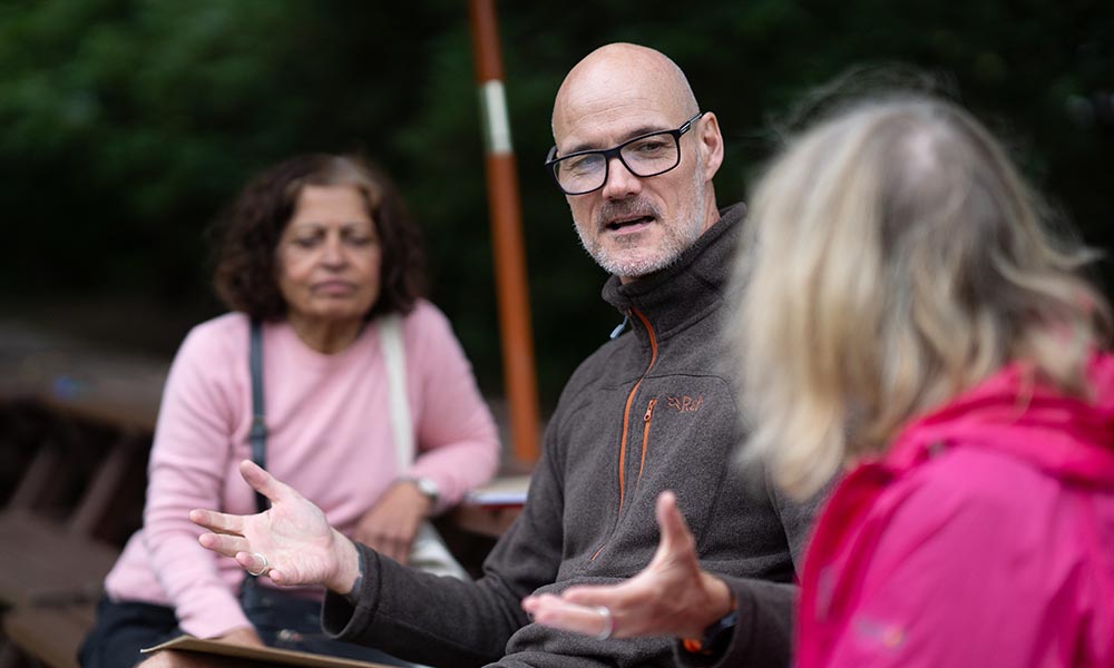 People out in the park having a discussion on a bench.