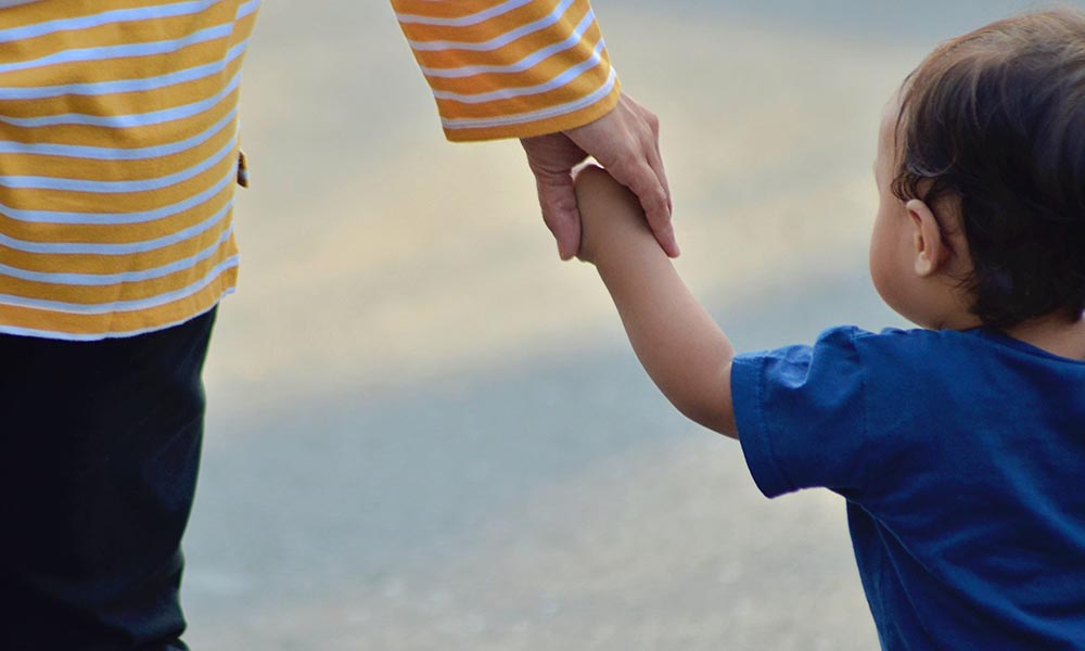A young child holding an adults hand.
