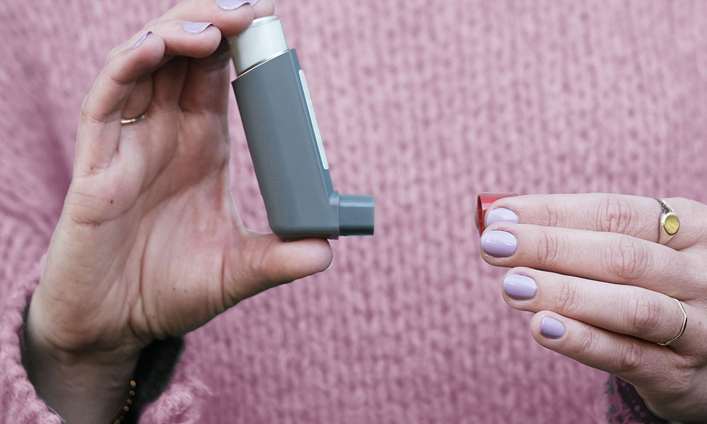 A women holding an inhaler with the cap off.